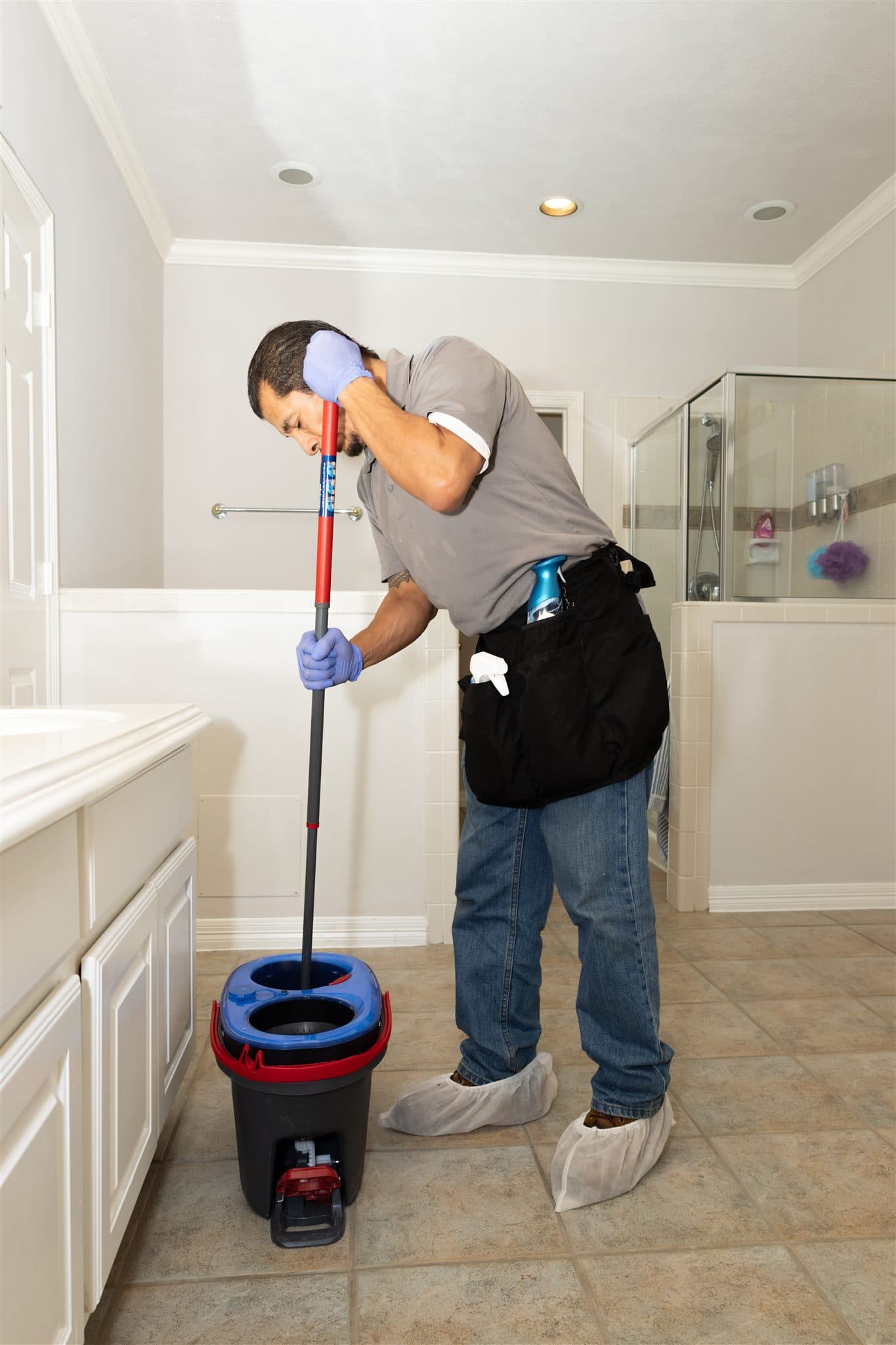 Cleaner mopping a glass shower area