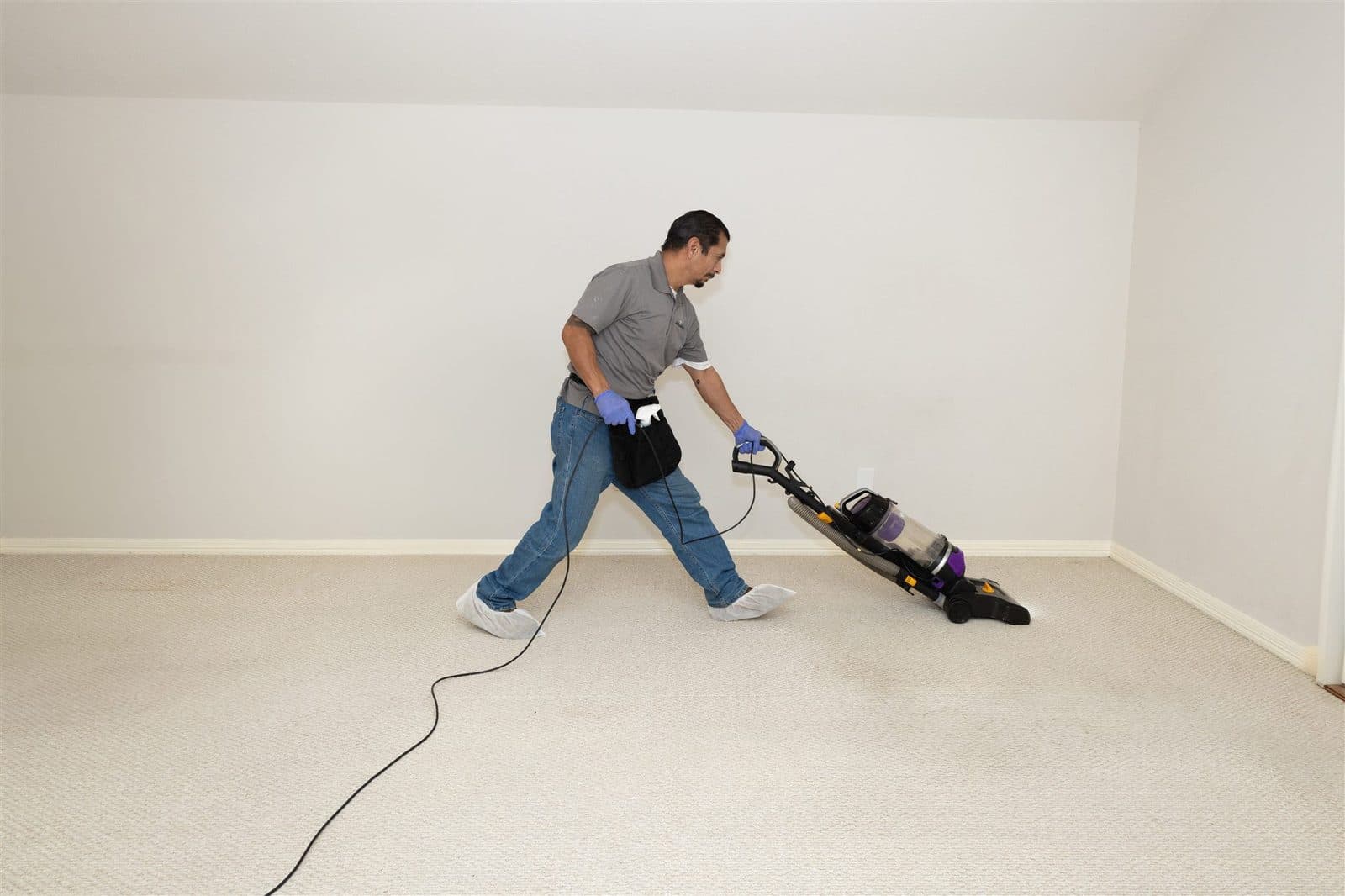 Mansion cleaner vacuuming an empty room after detail work